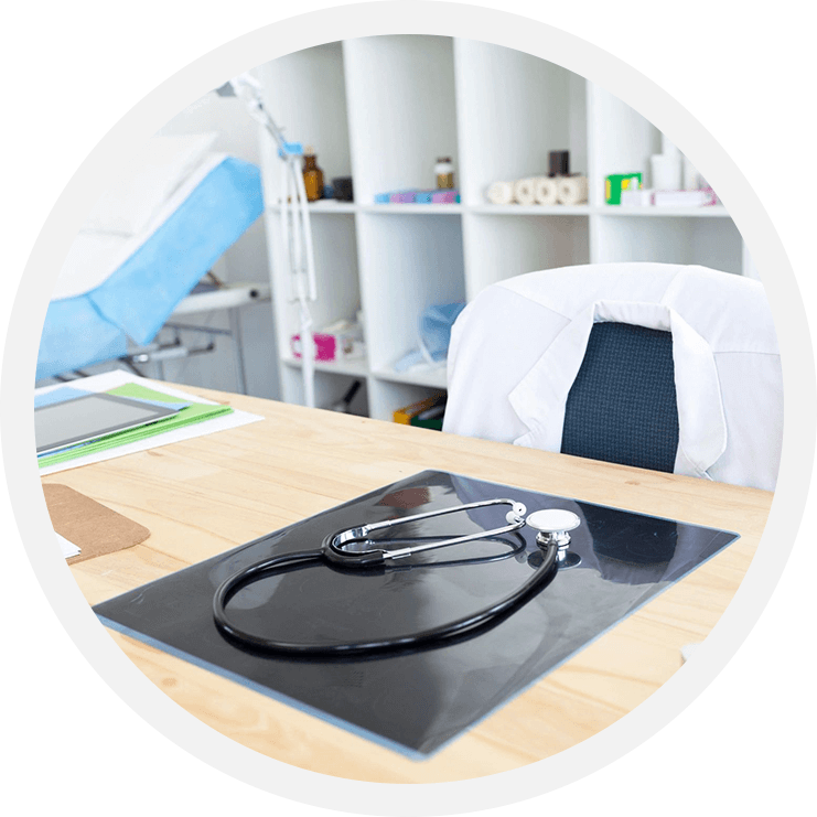 A stethoscope on top of a table in front of a laptop.